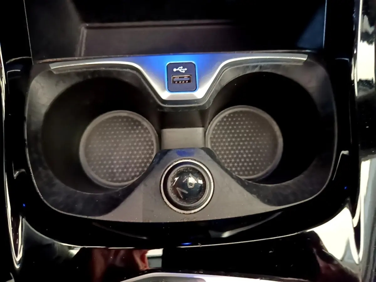 Gros plan sur les porte-gobelets et prise USB au centre de la console d’une BMW Série 1 118i Edition Sport bleue.