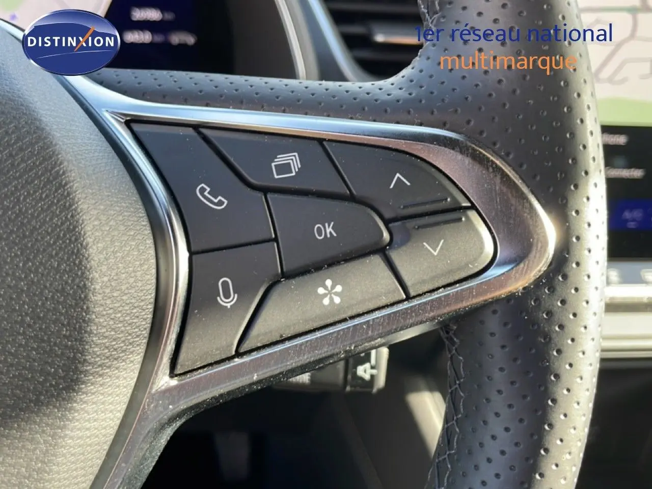 Gros plan sur les commandes multifonctions en cuir perforé du volant de la Renault Symbioz gris cassiopée métal, intérieur lumineux.