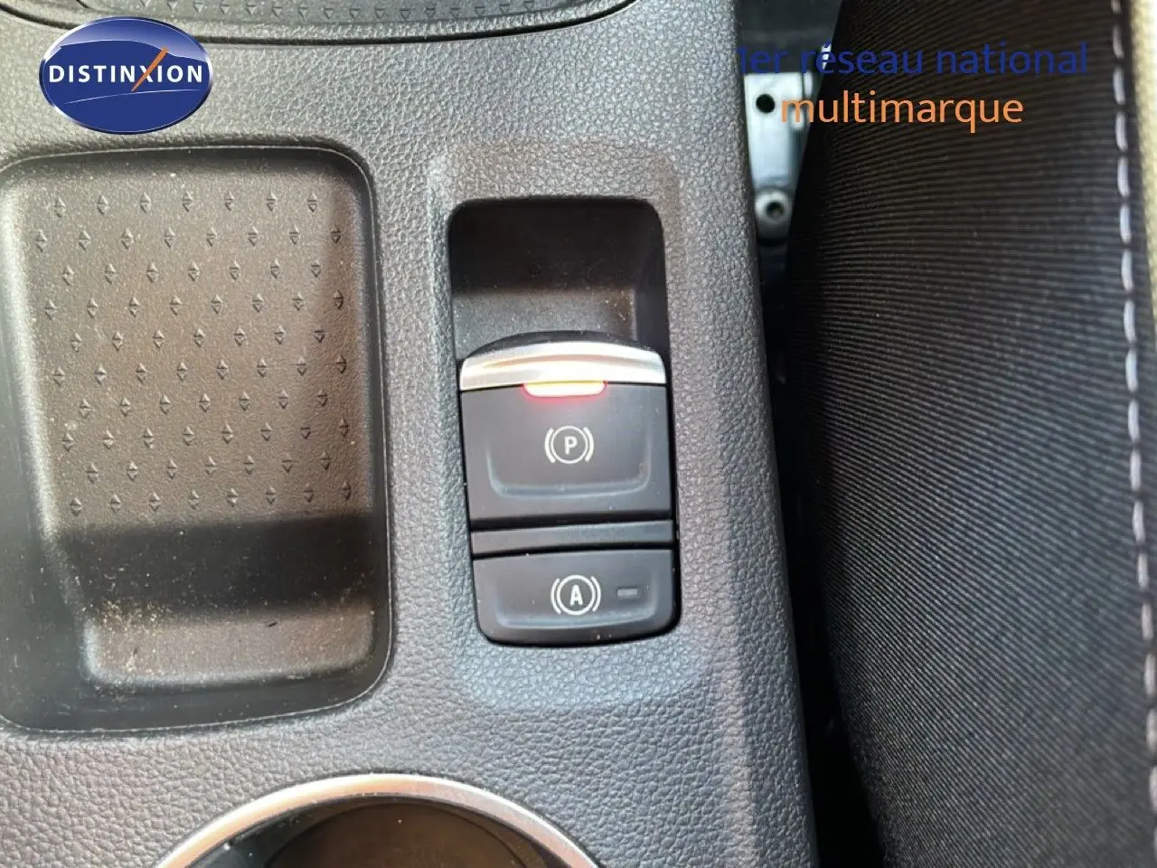 Gros plan sur les commandes de frein à main électronique et auto-hold dans l'habitacle du Renault Symbioz gris cassiopée.