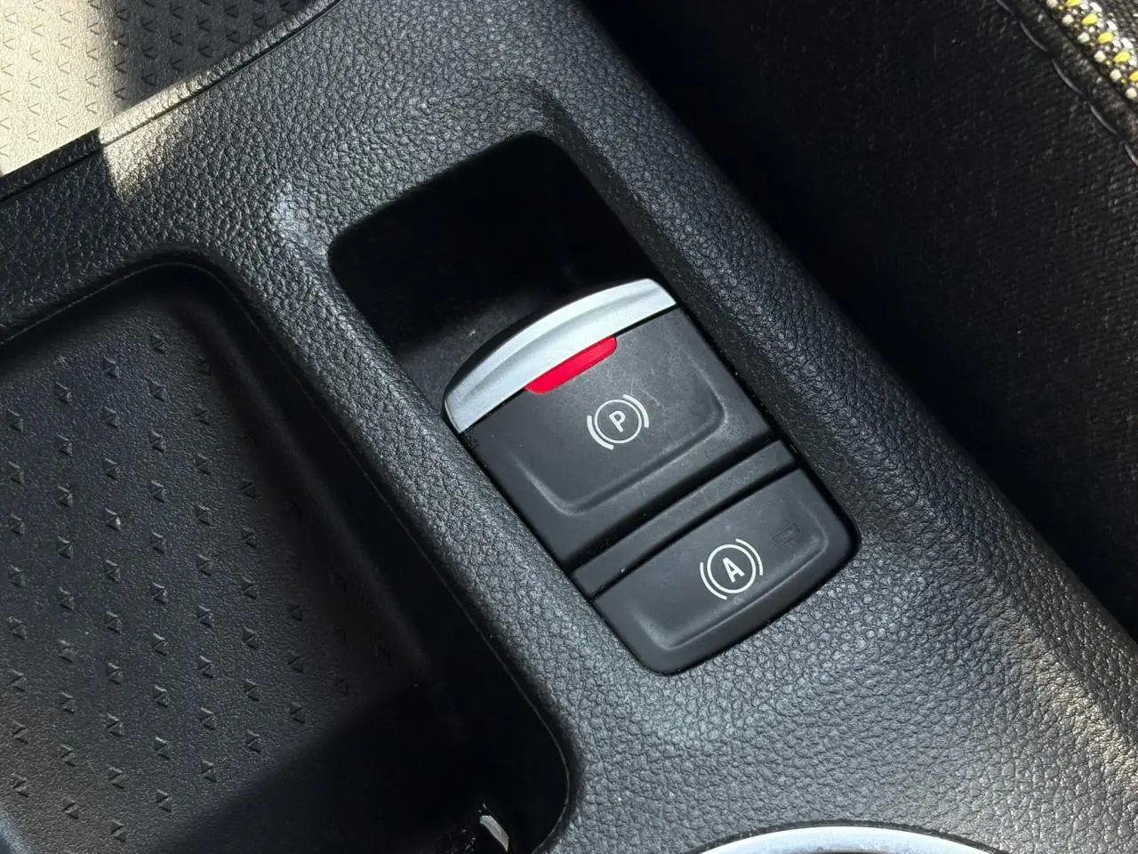 Gros plan sur la console centrale du Renault SYMBIOZ 2025, montrant les boutons de frein de parking électrique et auto-hold.