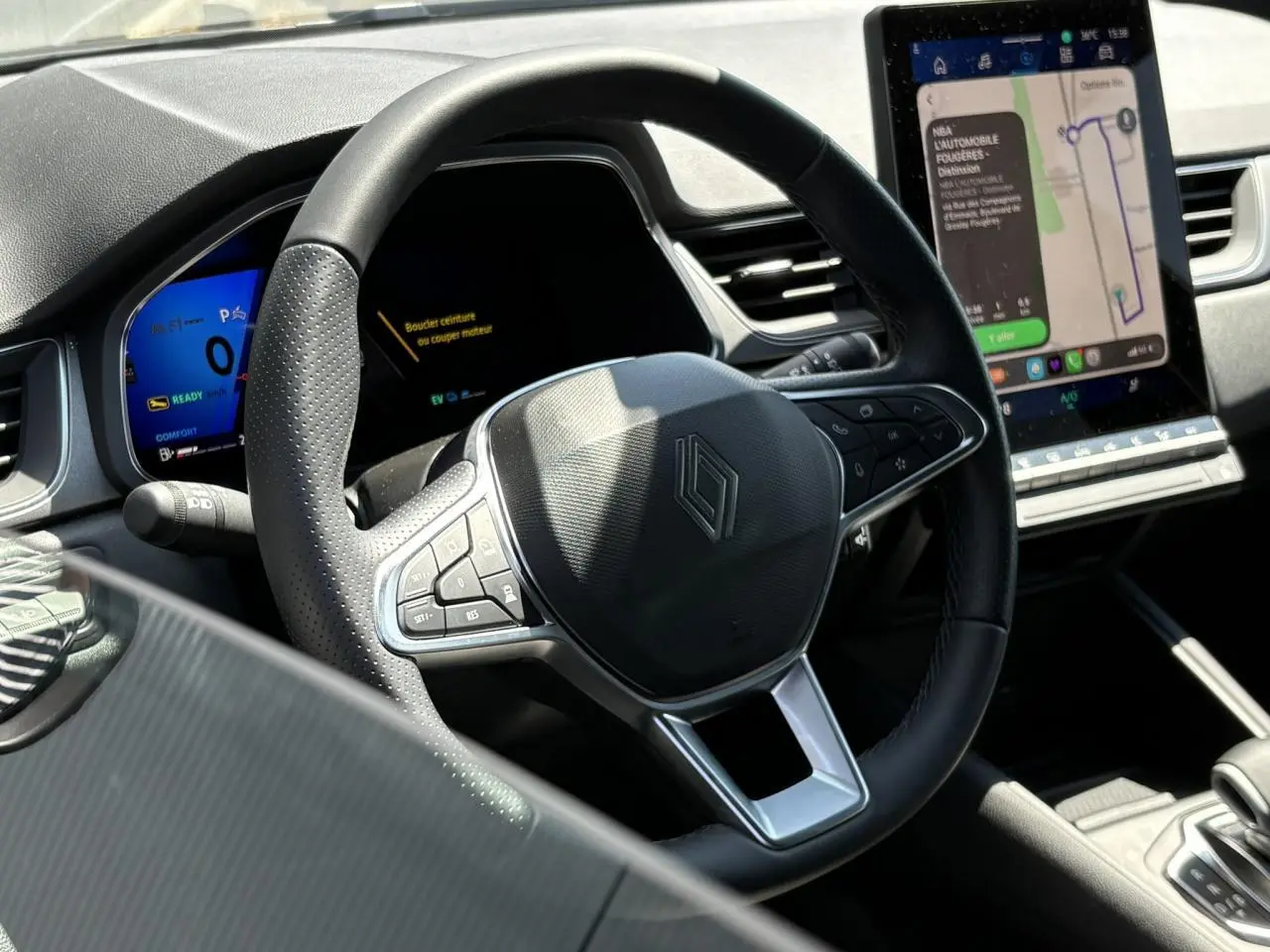 Vue intérieure centrée sur le volant Renault noir avec tableau de bord numérique et écran tactile vertical du Symbioz.