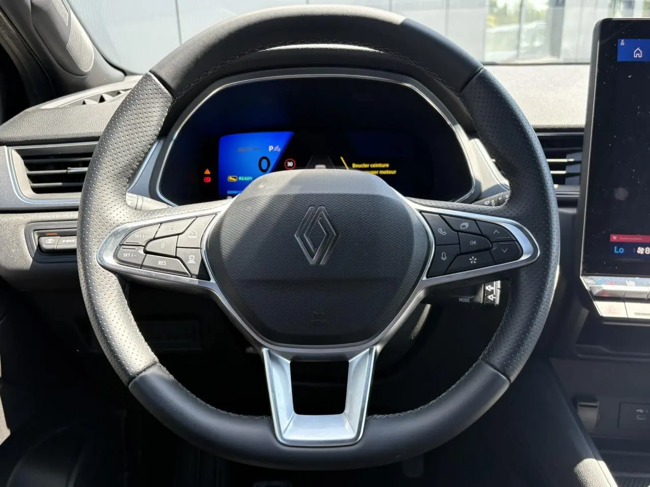 Vue rapprochée du volant noir perforé du Renault Symbioz E-Tech 2025 avec commandes intégrées et tableau de bord numérique.