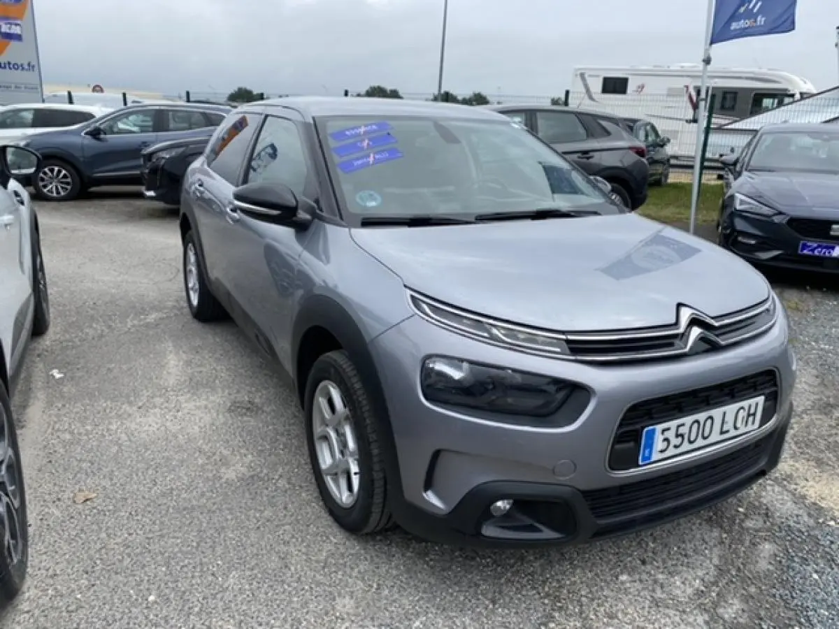 Citroën C4 Cactus gris clair vue 3/4 avant droit sur parking avec phares et calandre caractéristiques.