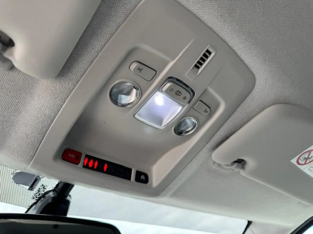 Vue intérieure du plafonnier gris clair du Citroën C4 Cactus 2020 avec éclairage et bouton SOS rouge allumé.