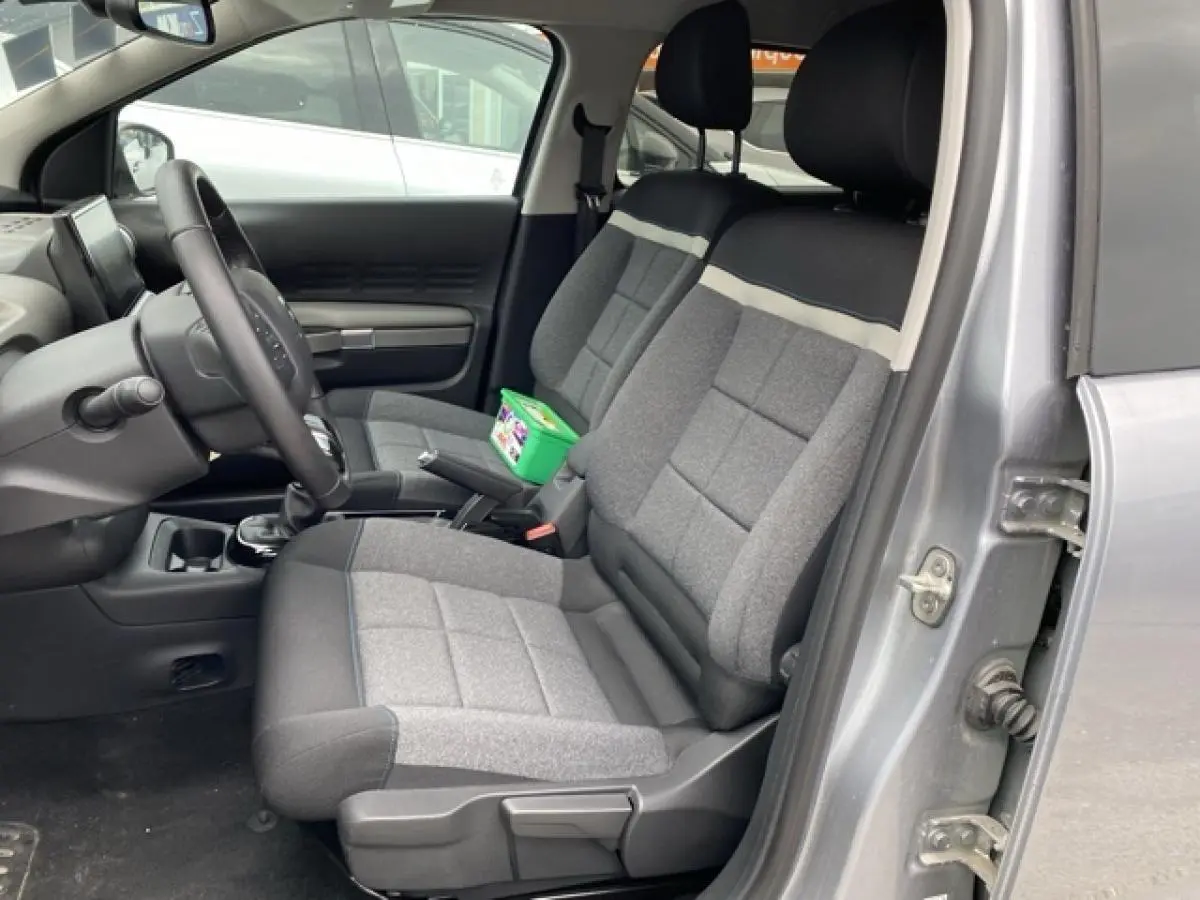 Vue intérieure côté conducteur de la Citroën C4 Cactus 2020 gris clair avec sièges tissu bicolores et volant réglable.