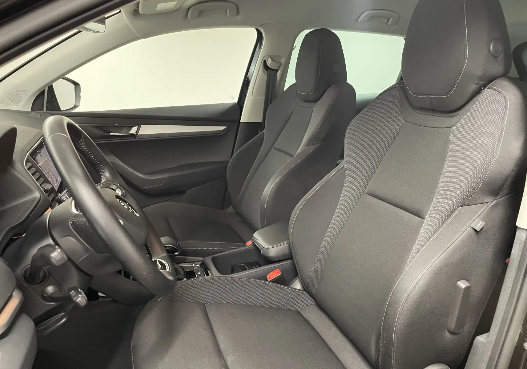 Vue intérieure côté conducteur du Skoda Karoq 2023 avec sièges noirs et tableau de bord digital visible.