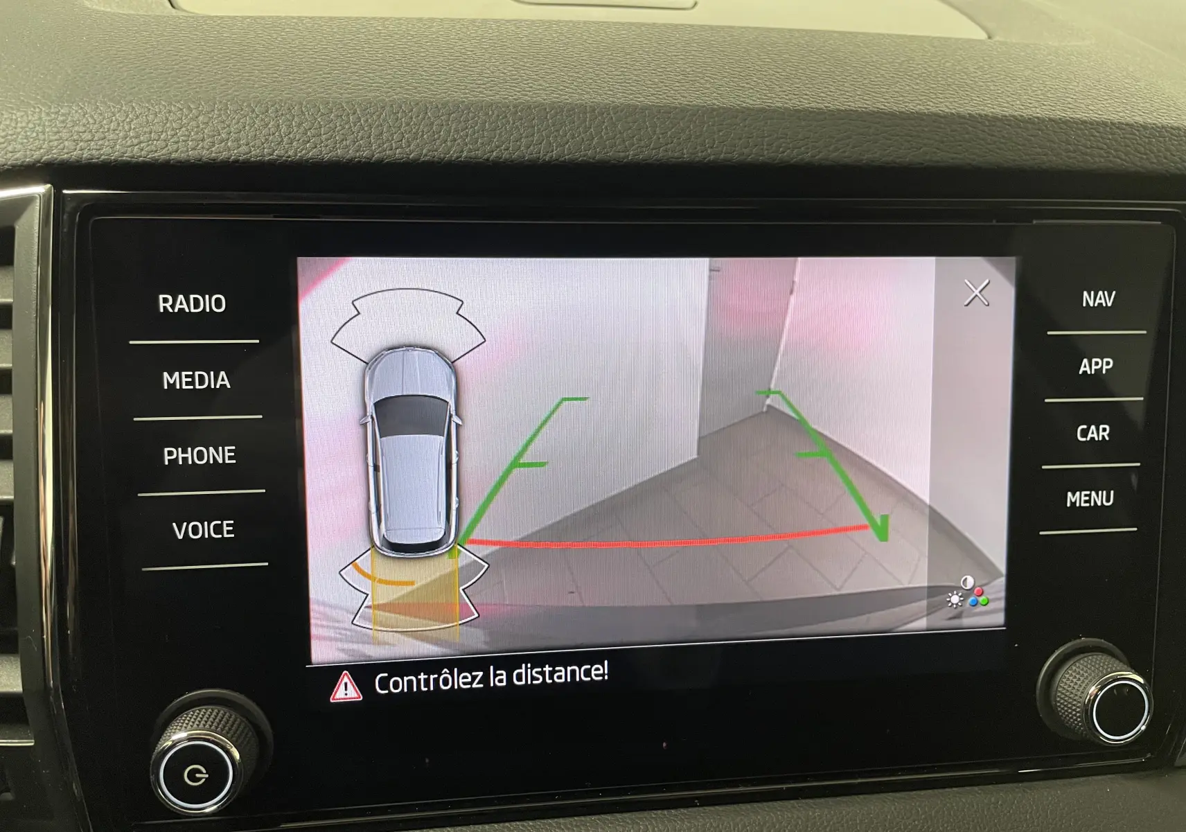 Écran multimédia montrant la caméra de recul avec vue arrière et capteurs d'aide au stationnement du Skoda Karoq noir nacré.