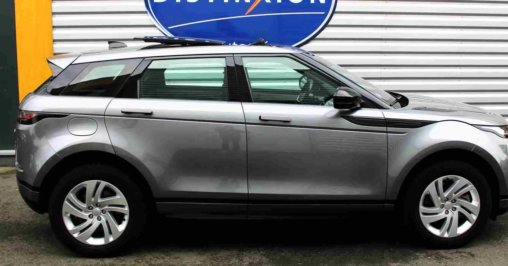 Vue intérieure côté gauche du Range Rover Evoque gris métal 2023, mettant en valeur les sièges bicolores et la console centrale moderne.