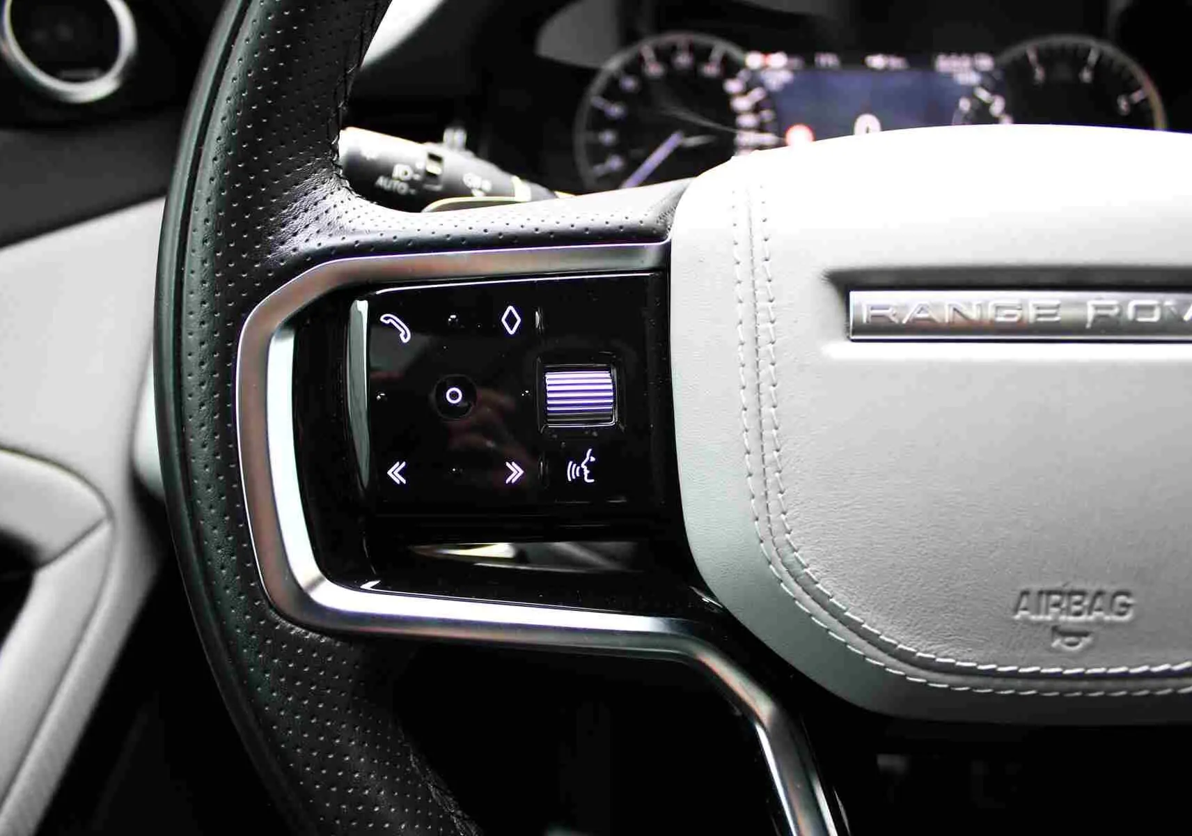 Gros plan sur la grille d’aération arrière avec plaque Range Rover Evoque, intérieur noir du SUV hybride gris métal 2023.