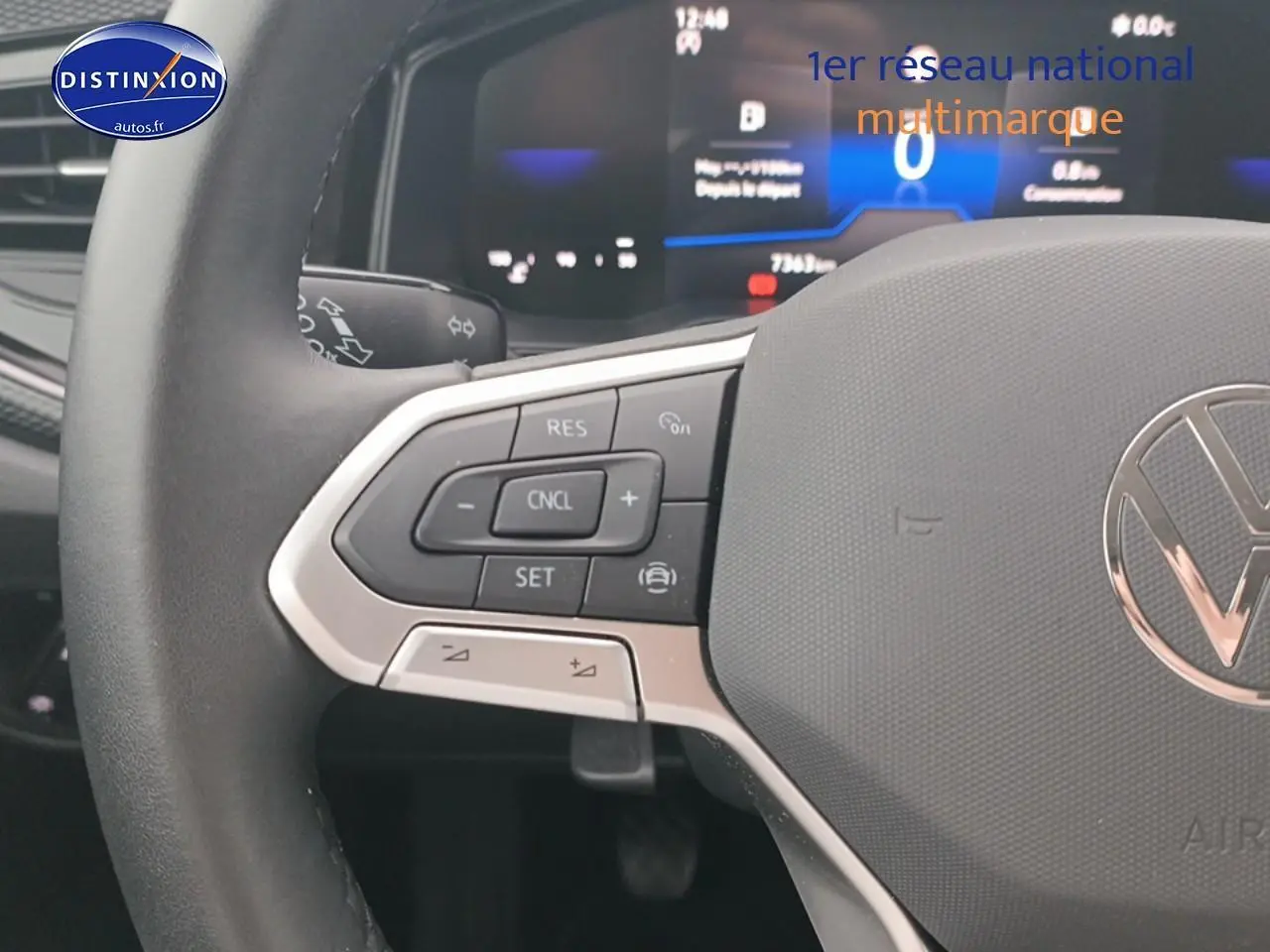 Gros plan sur le volant multifonction noir avec commandes de régulateur de vitesse de la Volkswagen Polo blanche.