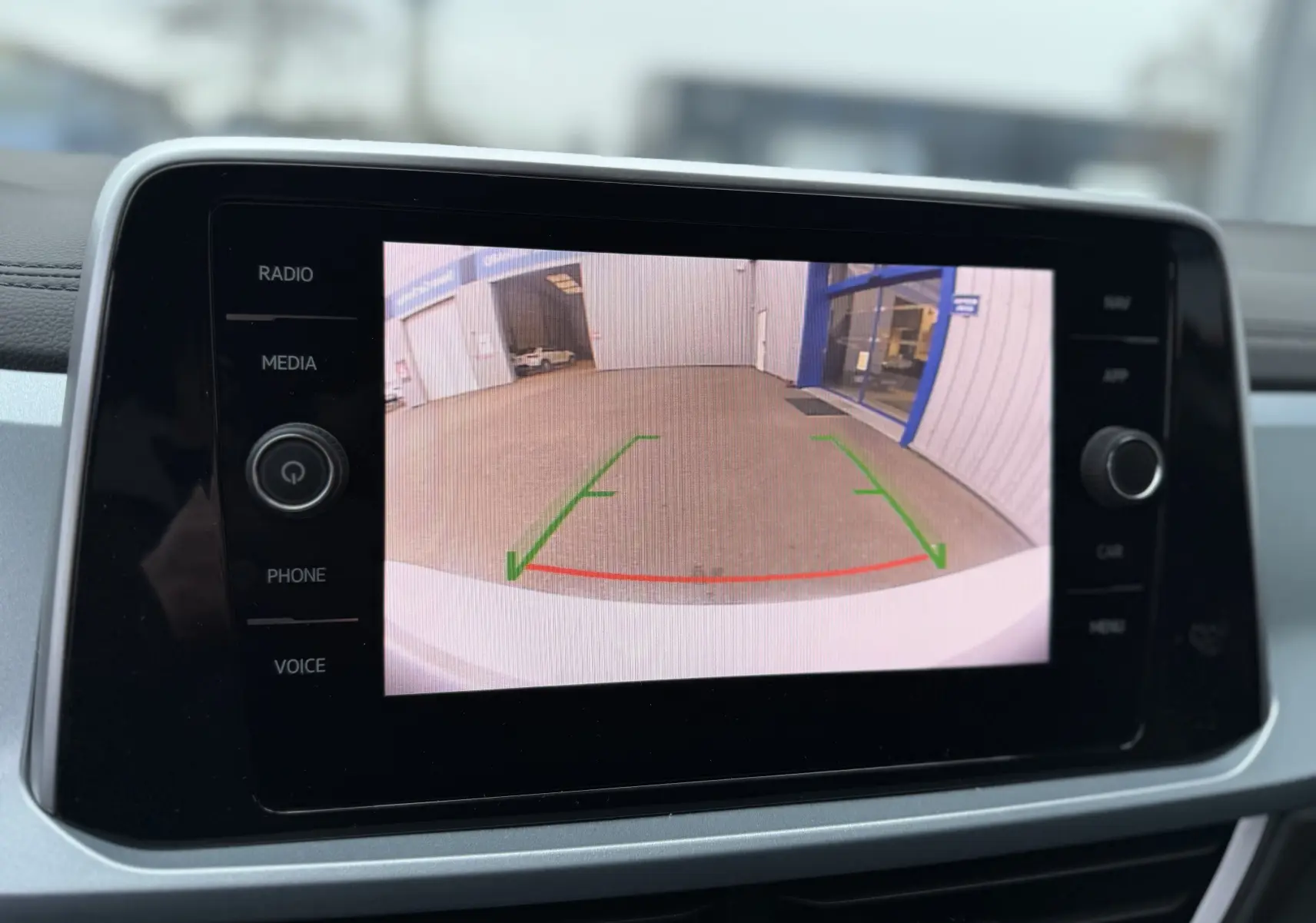 Écran central affichant la caméra de recul du Volkswagen T-Roc blanc toit noir, vue arrière avec lignes de guidage vertes et rouges.