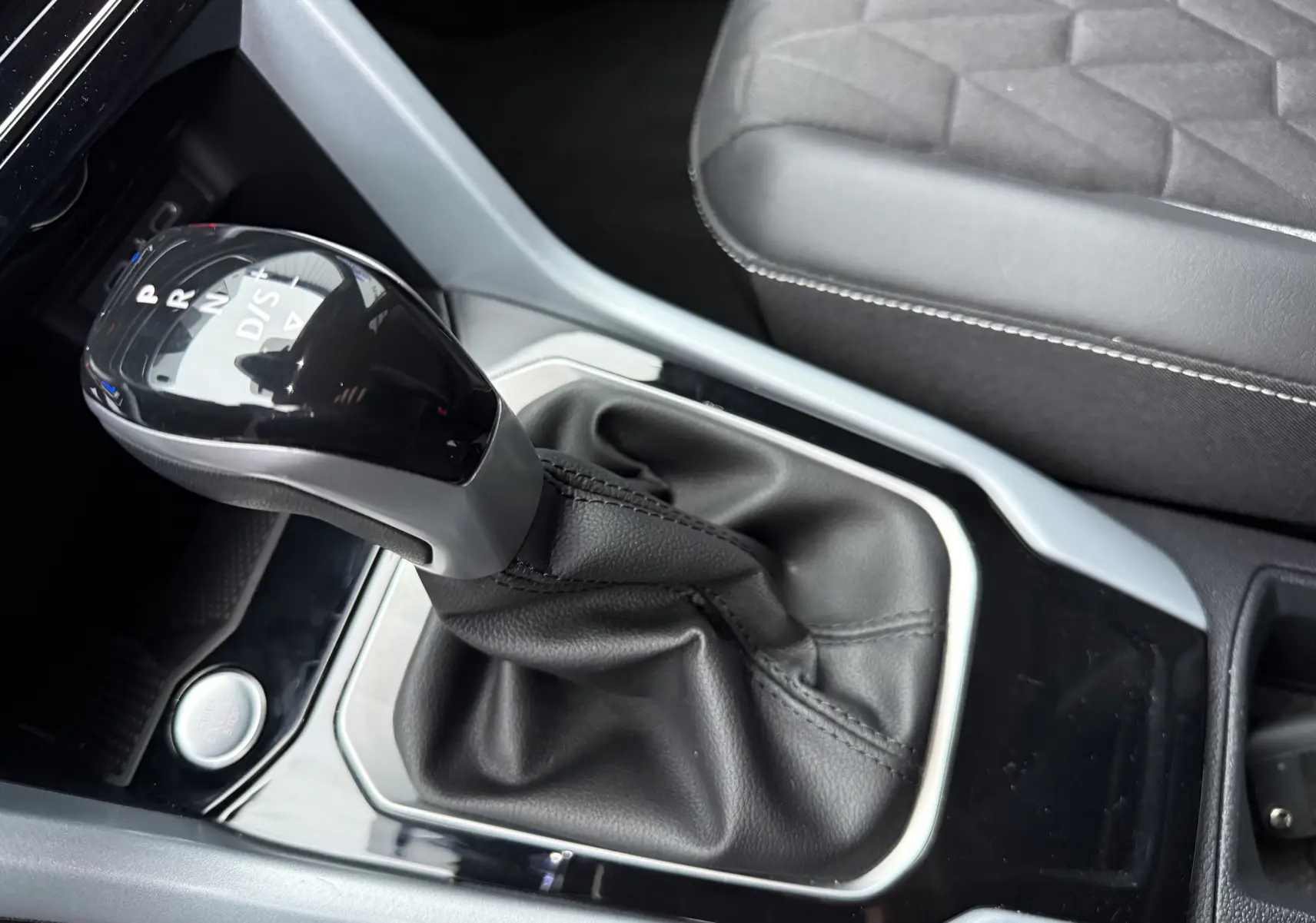 Gros plan sur le levier de vitesses automatique noir et gris du Volkswagen T-Roc 2025, avec sellerie noire visible.