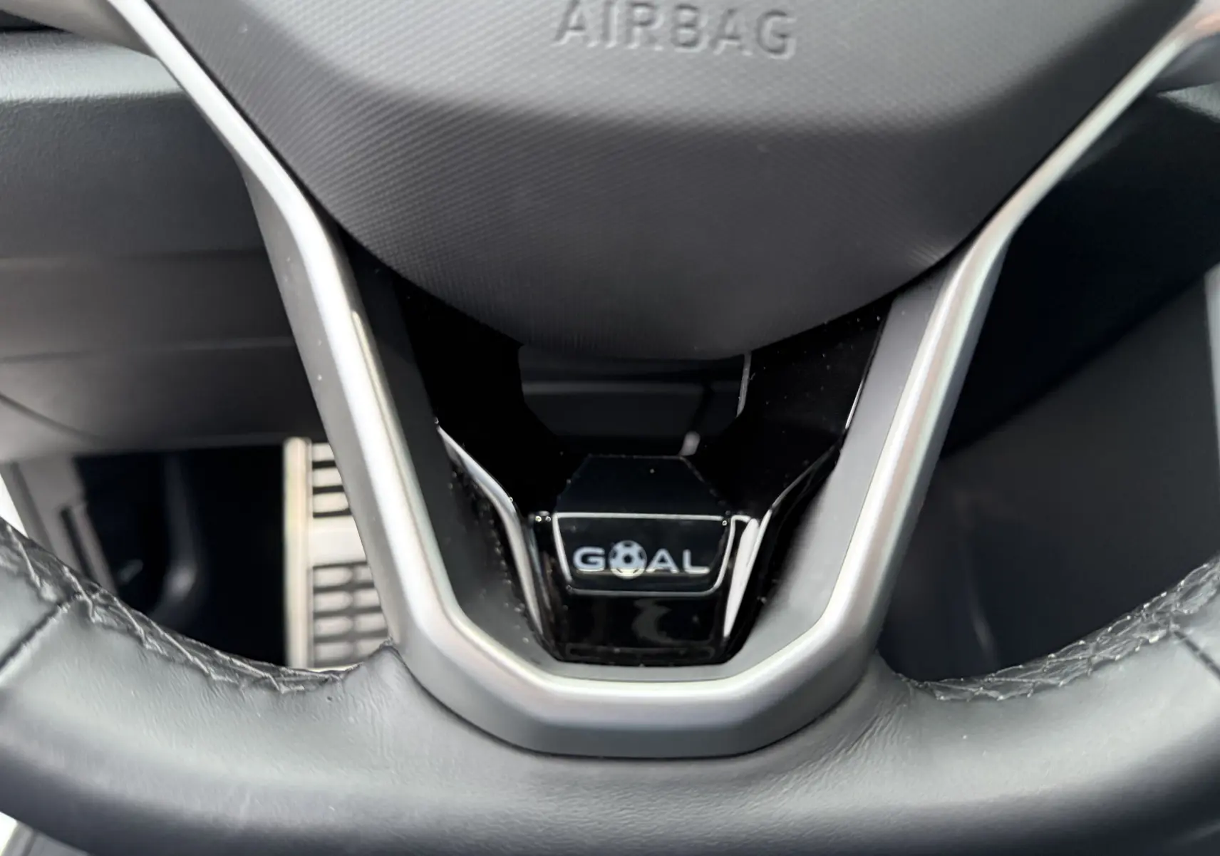 Gros plan sur le volant noir du Volkswagen T-Roc 2025 avec logo "GOAL" et inscription "AIRBAG" visible.