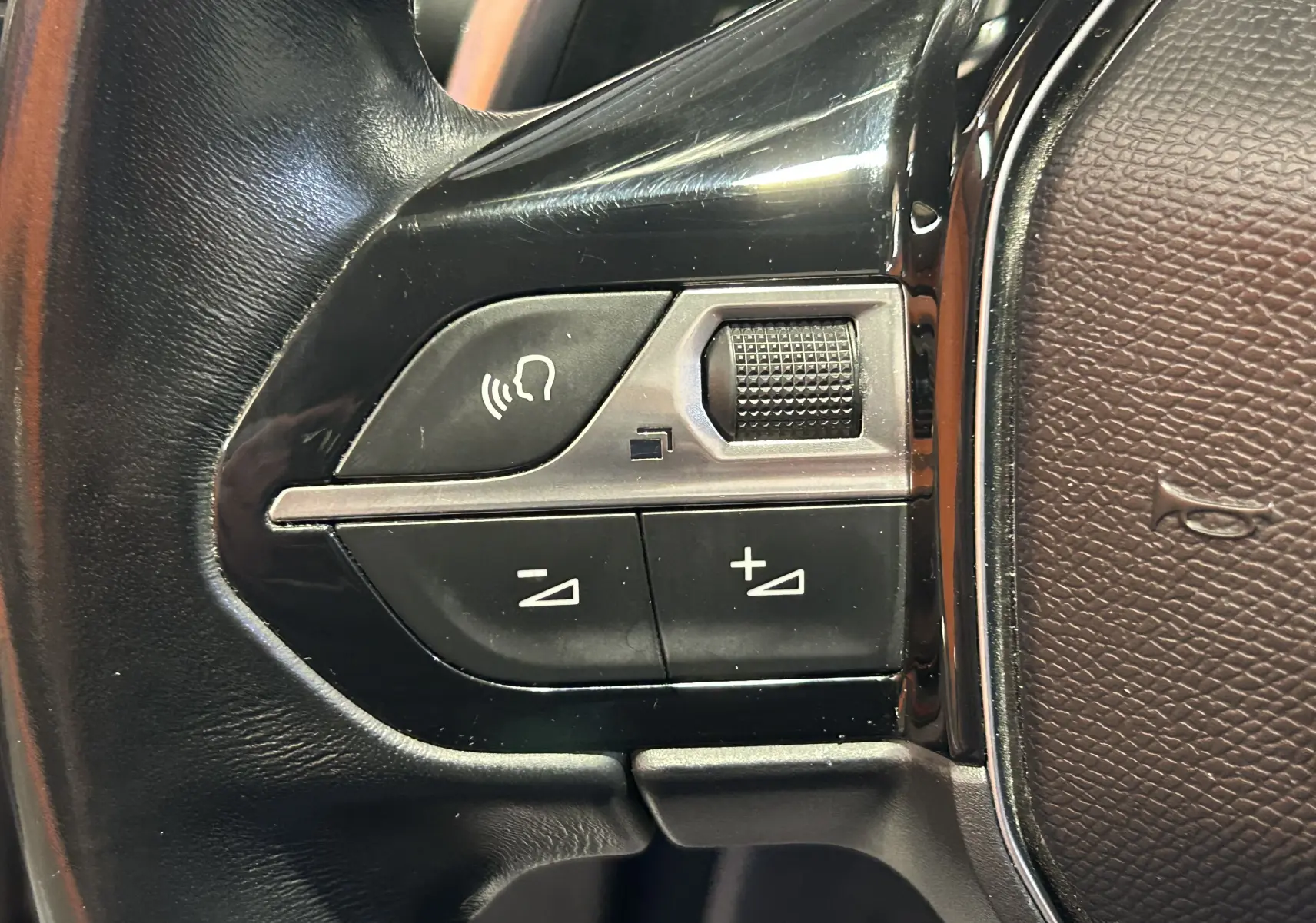 Gros plan sur les commandes de volume et de reconnaissance vocale sur le volant en cuir noir du Peugeot 508 SW.