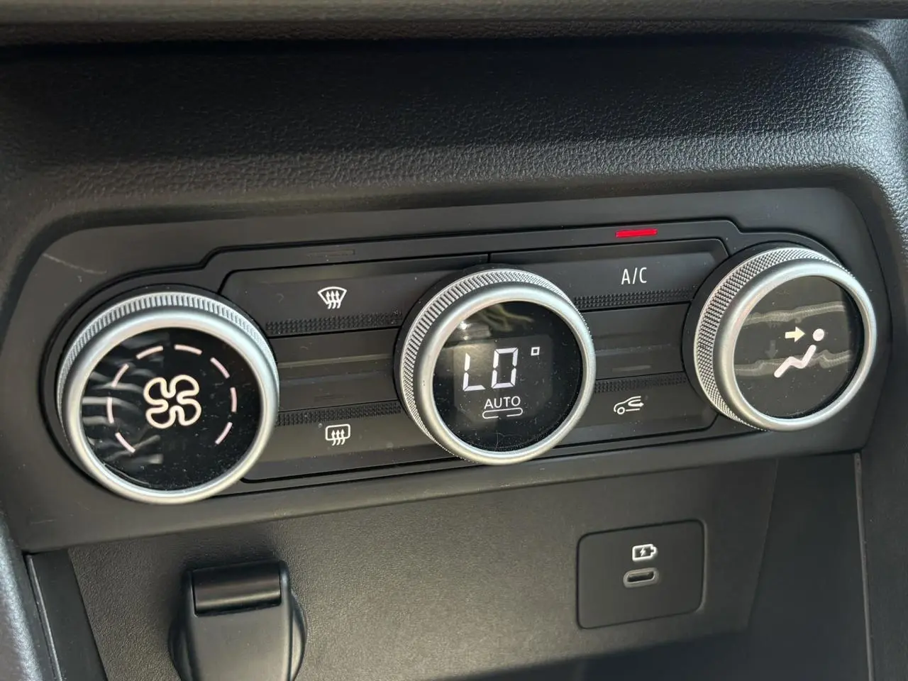 Gros plan sur les commandes de climatisation automatique du Dacia Sandero Stepway beige, avec affichage digital et réglages rotatifs.