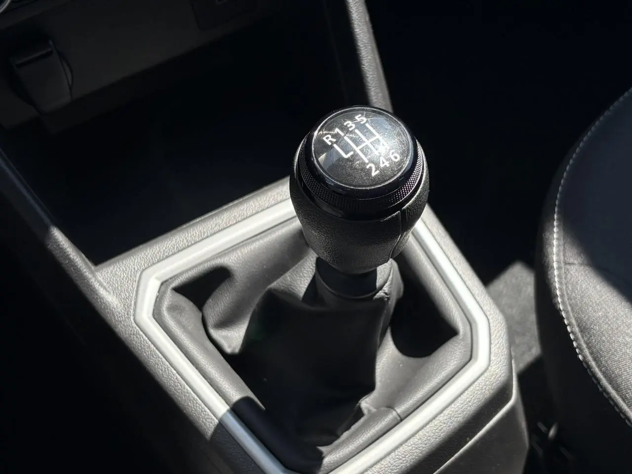 Gros plan sur le levier de vitesses manuel noir de la Dacia Sandero Stepway 2025, intérieur gris et siège tissu visible.