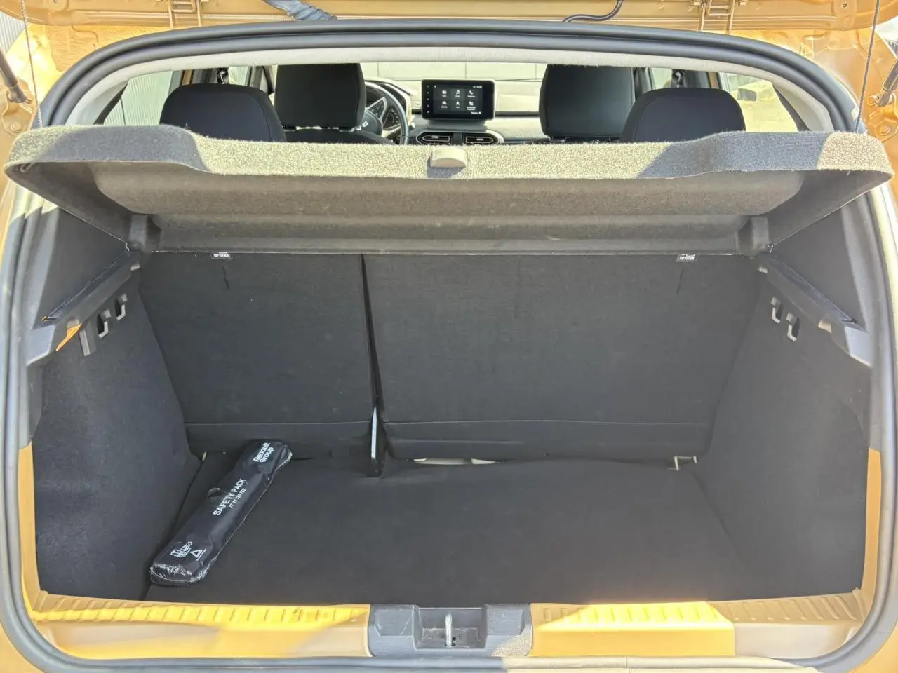 Coffre ouvert d’une Dacia Sandero Stepway Beige Safari, vue arrière montrant l’espace de chargement et l’écran tactile du tableau de bord.