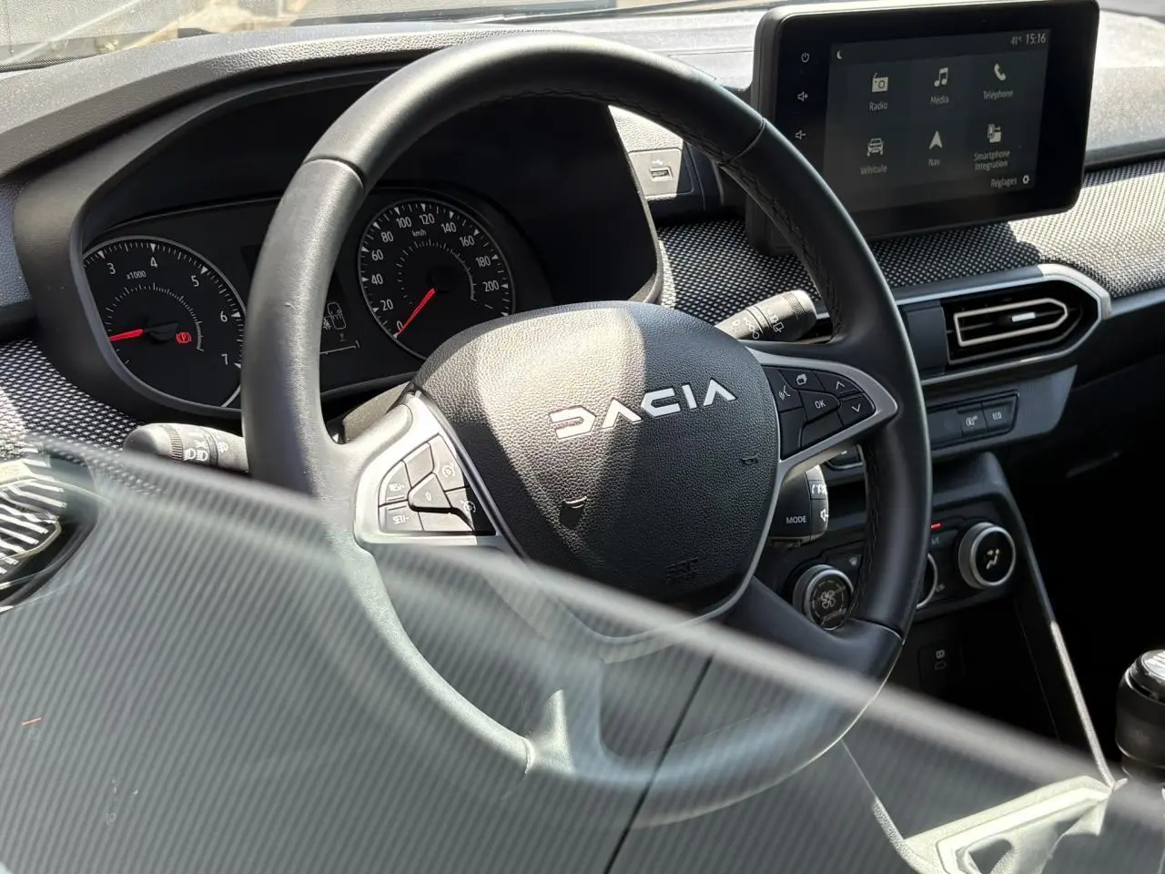Vue rapprochée du volant noir Dacia et du tableau de bord avec écran tactile dans l'habitacle du Sandero Stepway 2025.