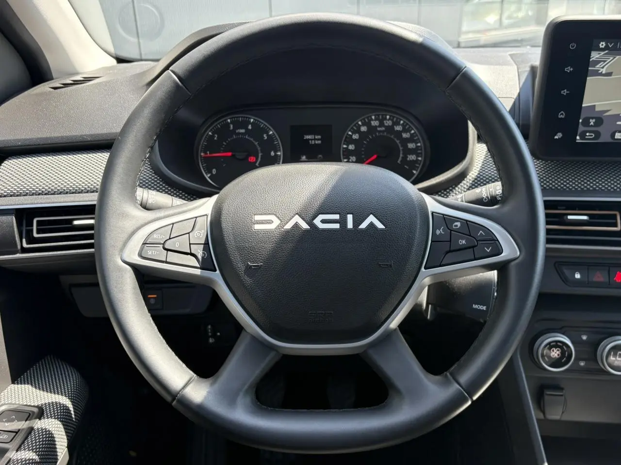 Vue rapprochée du volant noir de la Dacia Sandero Stepway 2025 avec commandes intégrées et tableau de bord numérique.