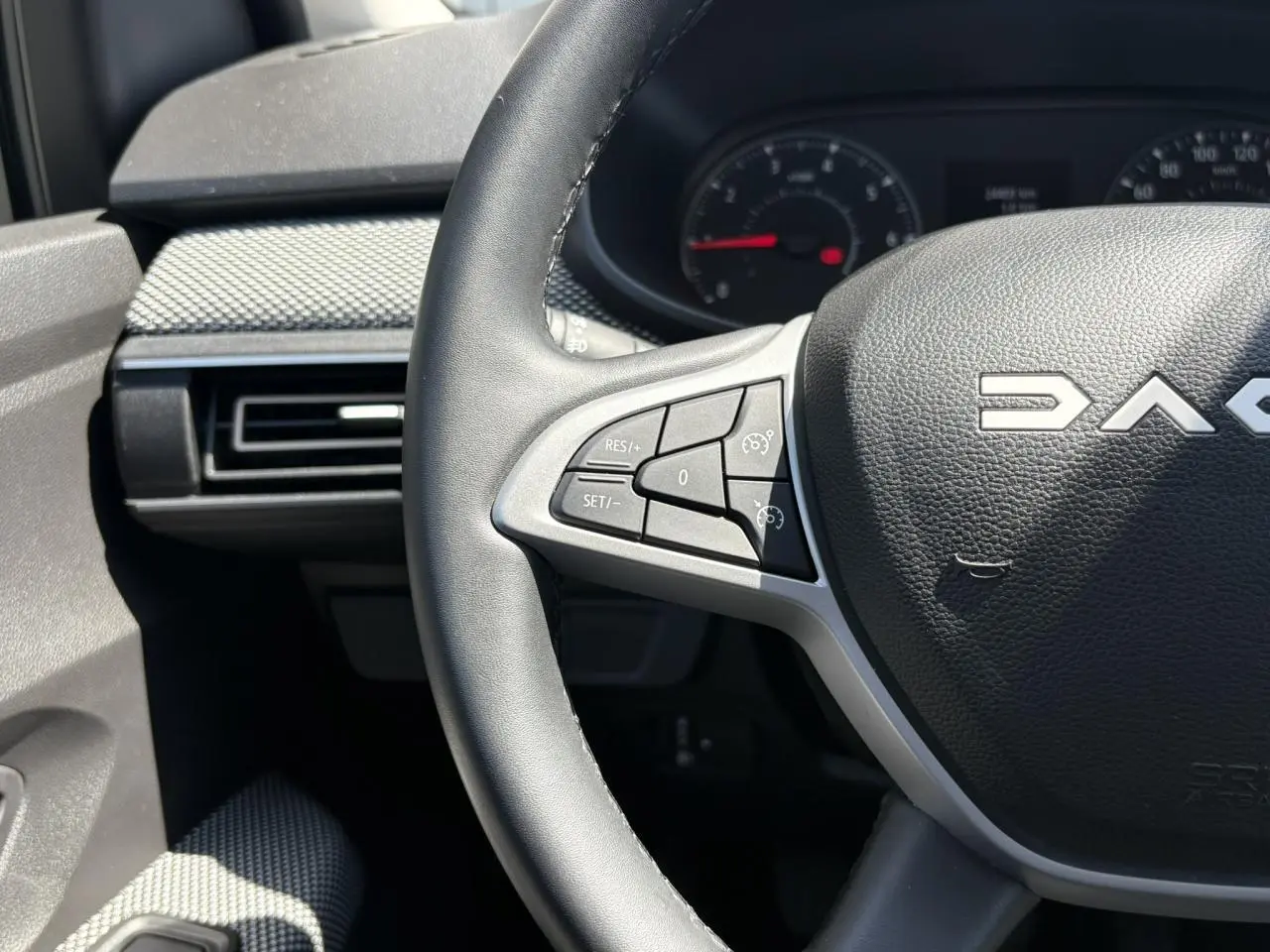 Gros plan sur le volant noir de la Dacia Sandero Stepway 2025 avec commandes intégrées côté gauche et tableau de bord partiel.
