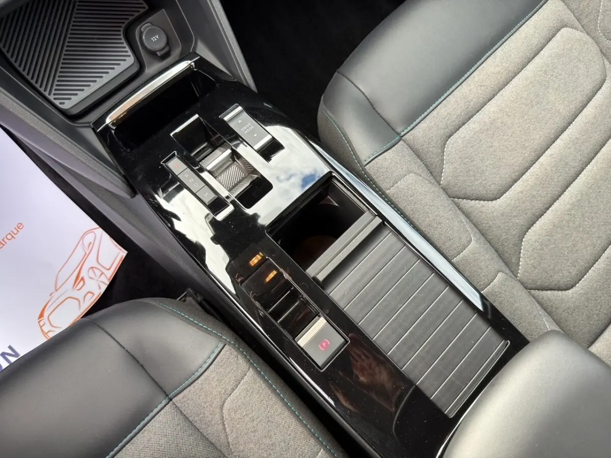Vue plongeante sur la console centrale noire brillante et les sièges gris avec surpiqûres bleues de la Citroën C4 2023.