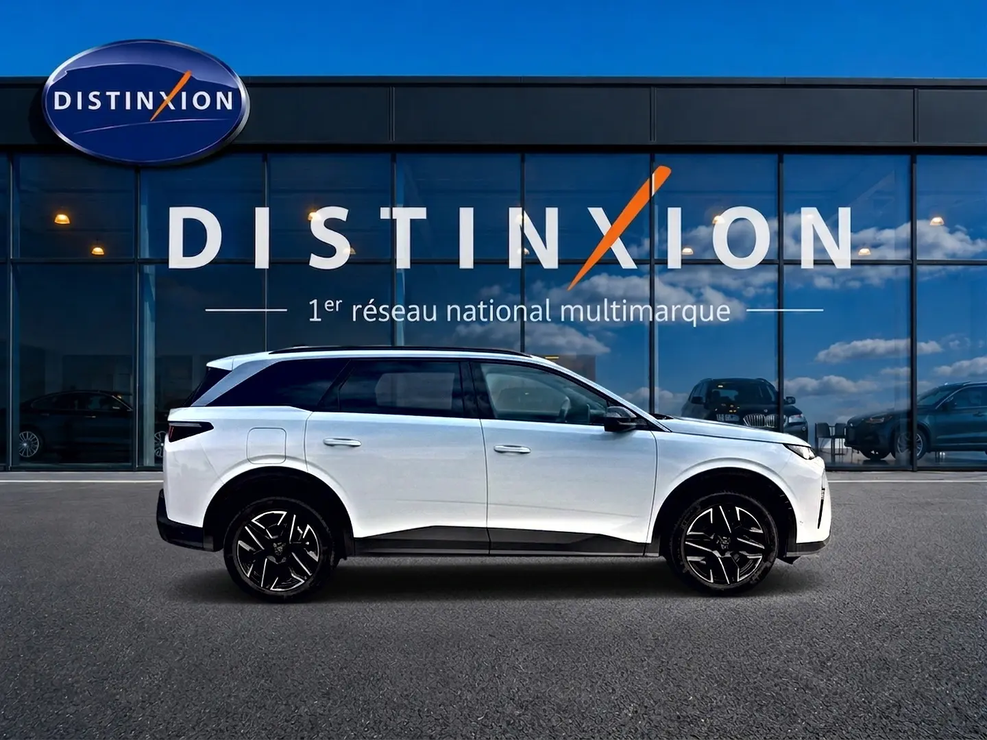 Profil droit du SUV Peugeot 5008 blanc 2025 avec jantes noires devant une vitrine Distinxion.