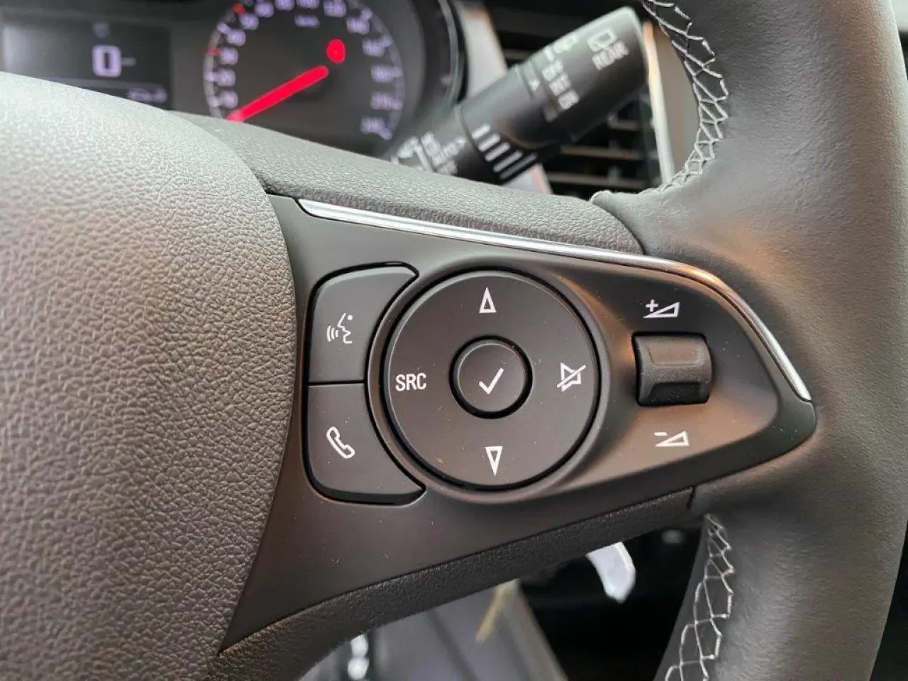 Gros plan sur les commandes du volant en cuir noir de l’Opel Crossland gris métallisé, avec boutons multifonctions visibles.