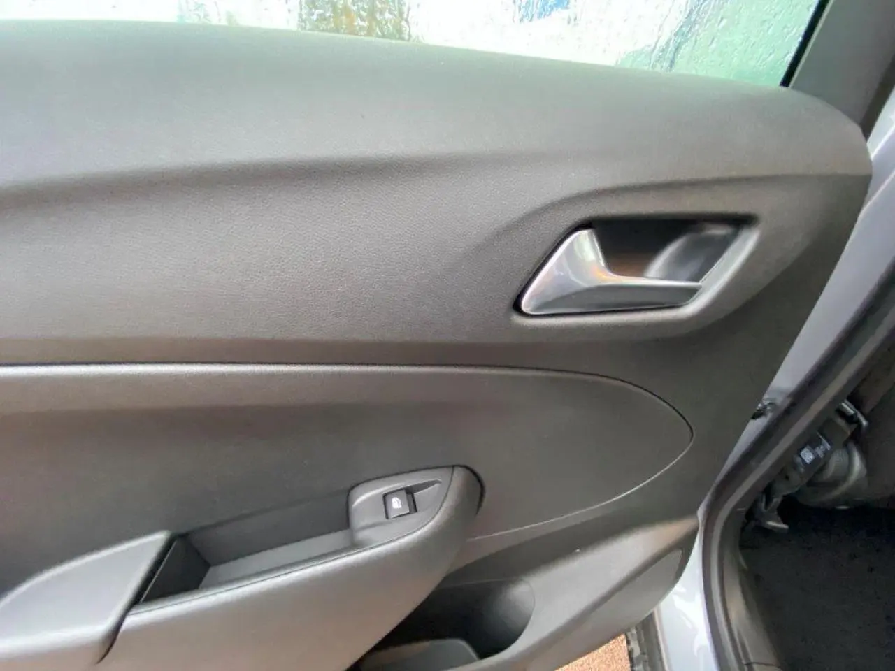 Gros plan sur la porte intérieure côté conducteur de l'Opel Crossland gris métallisé, avec poignée et bouton de verrouillage.