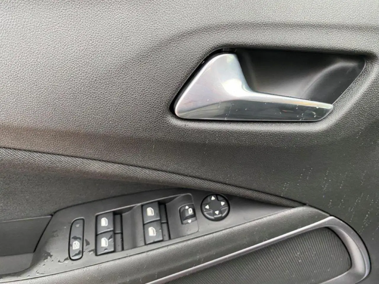 Poignée intérieure et commandes des vitres côté gauche d'un Opel Crossland gris métallisé 2022 en gros plan.