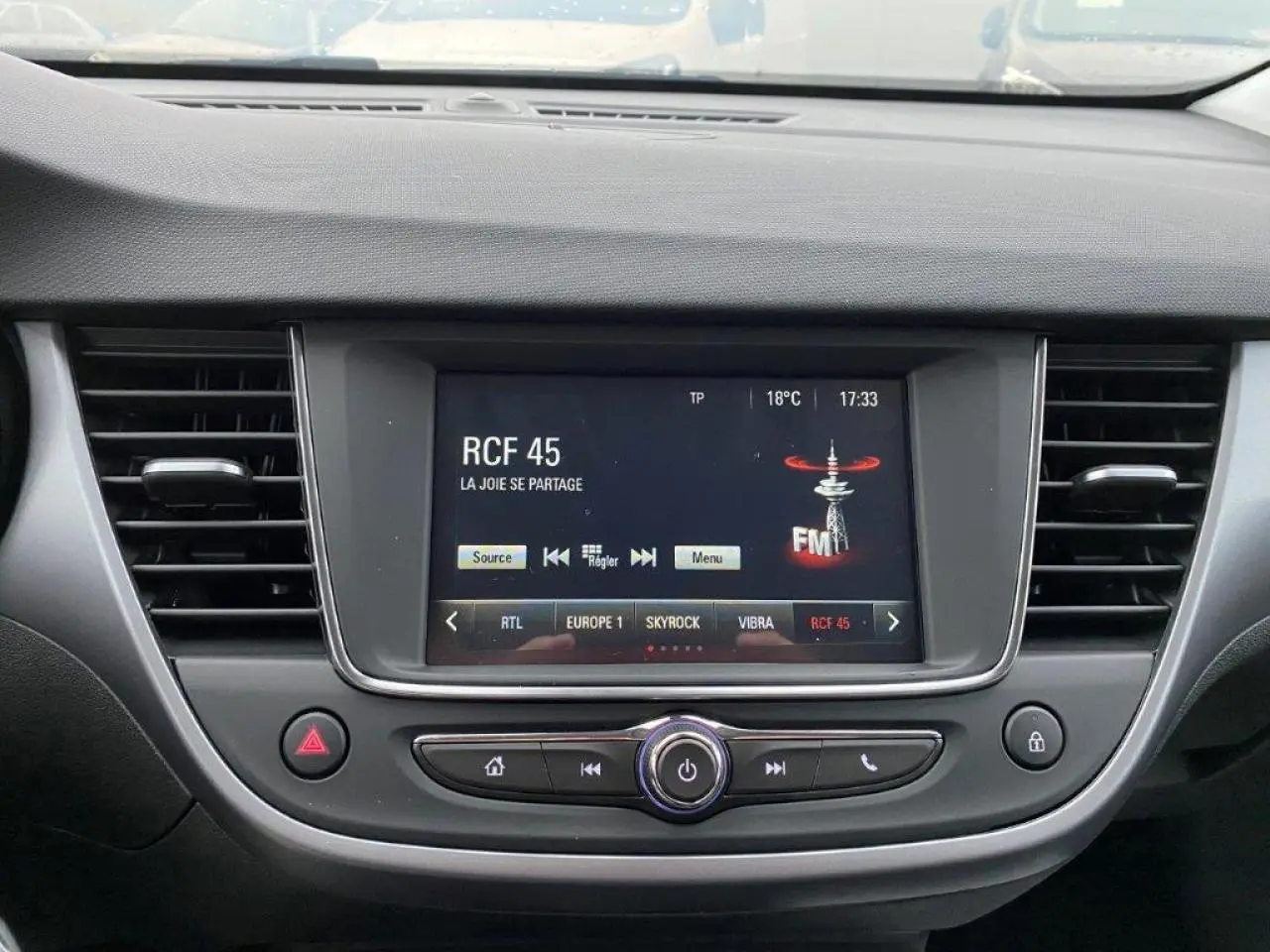 Vue rapprochée de l'écran tactile multimédia central de l'Opel Crossland gris métallisé, affichant une radio FM.