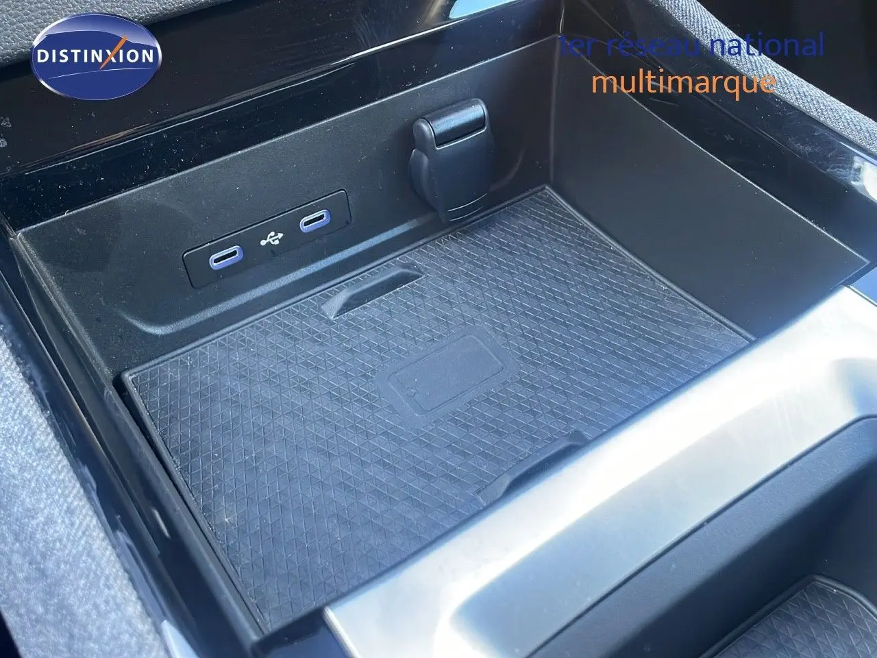 Gros plan sur la console centrale noire du Renault Austral blanc glacier, montrant les ports USB et un espace de rangement.