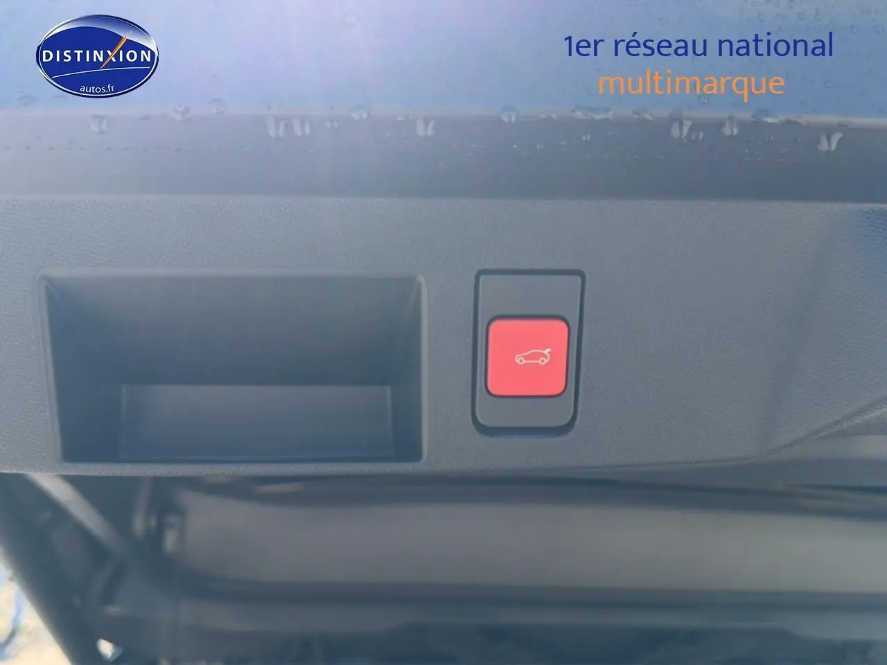 Gros plan sur le bouton rouge d'ouverture du hayon du Citroën C5 Aircross blanc et noir, vue intérieure arrière du coffre.