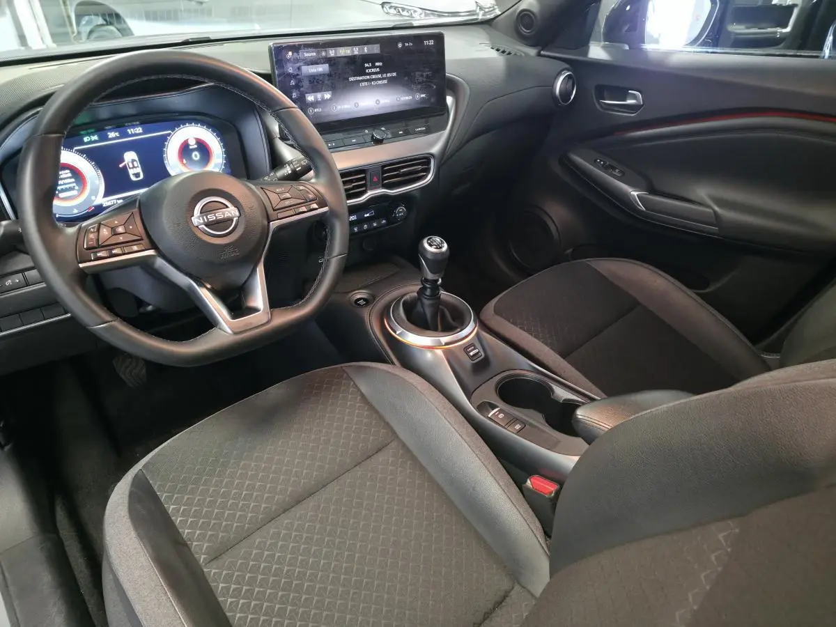 Vue intérieure côté conducteur du Nissan Juke 2025 gris, volant cuir, écran tactile 12,3 pouces et boîte manuelle.