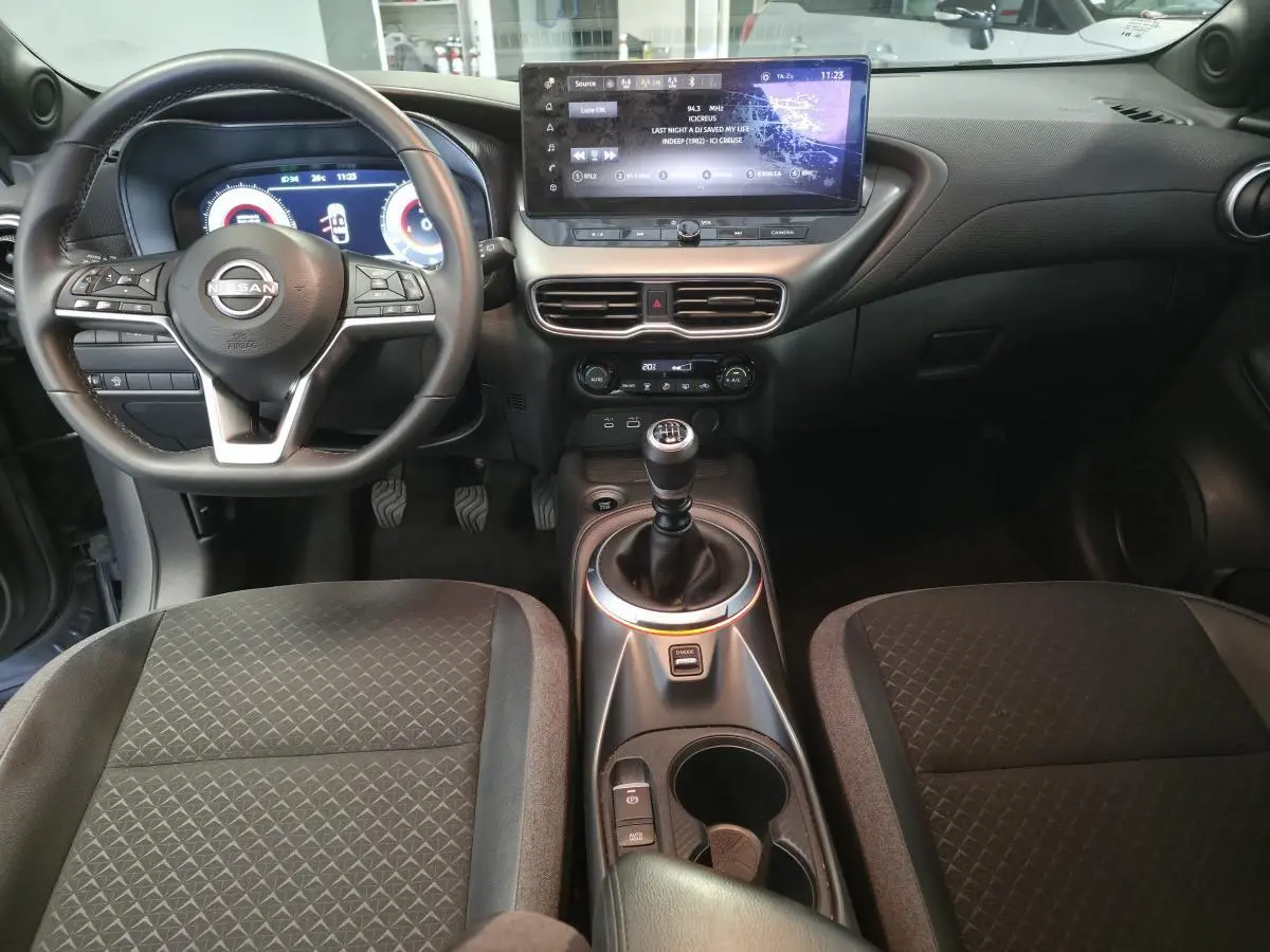 Vue intérieure avant du Nissan Juke 2025 avec volant cuir, écran tactile central 12,3 pouces et levier de vitesses manuel.