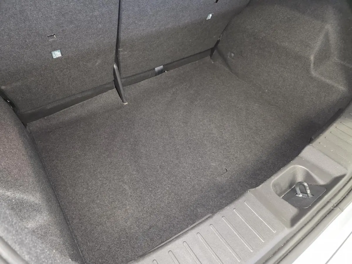 Coffre vide vu de dessus du Nissan Juke 2025 gris, avec tapis de sol et ancrage visible.