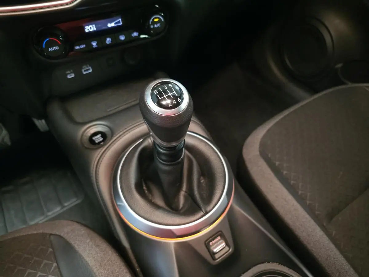 Gros plan sur le levier de vitesses manuel noir et gris dans l’habitacle sombre du Nissan Juke 2025.