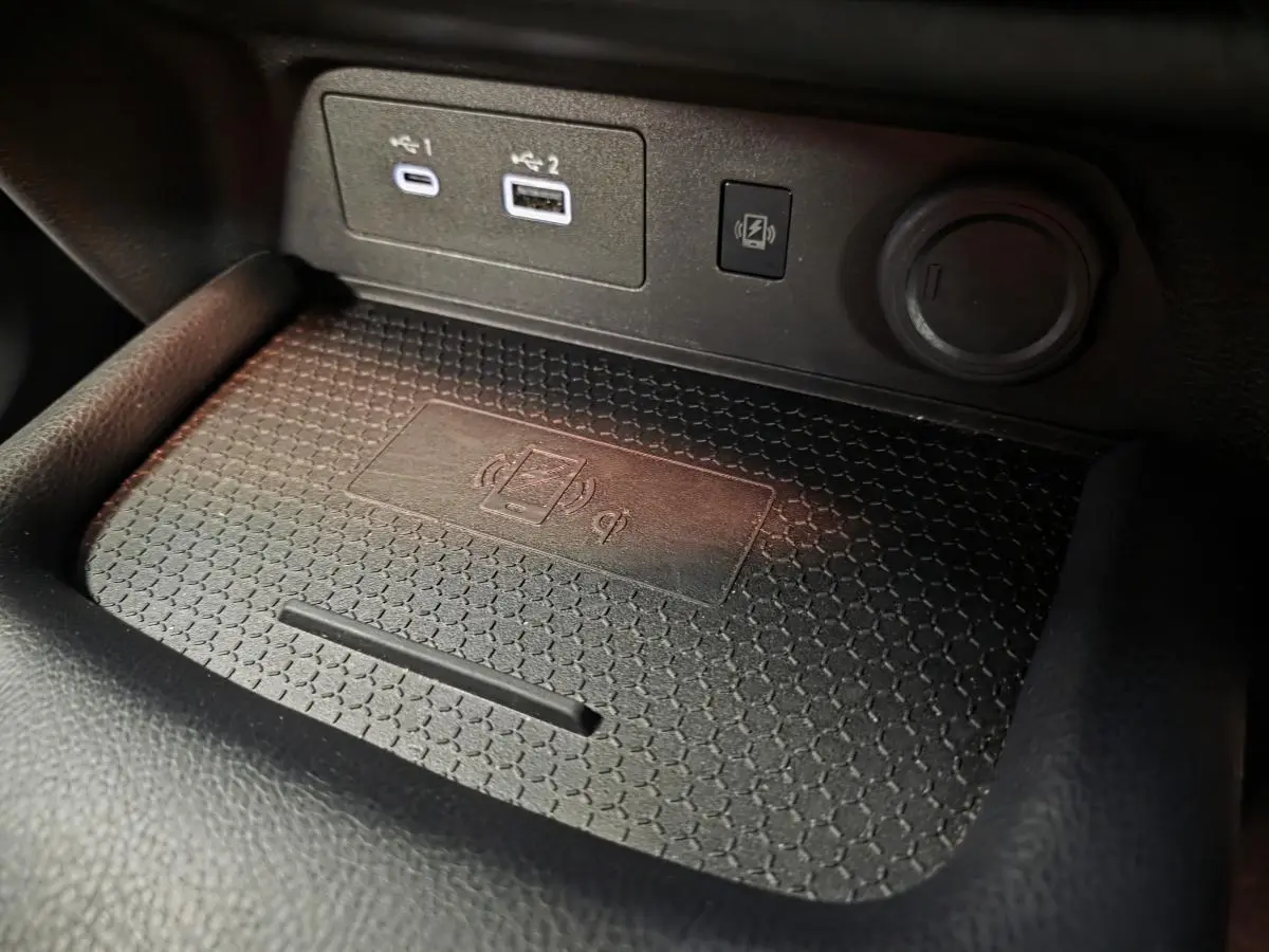 Gros plan sur la zone de recharge sans fil et ports USB du Nissan Juke gris, intérieur noir texturé.