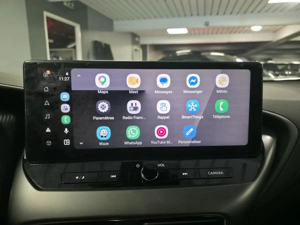Écran tactile central du Nissan Juke 2025 affichant des applications de navigation et communication, intérieur noir.