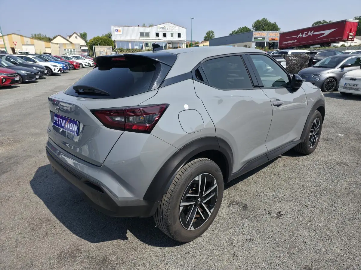 Nissan Juke gris métallisé vue 3/4 arrière droit avec jantes alliage et vitres teintées sur parking.