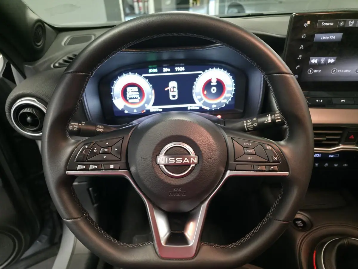 Vue rapprochée du volant en cuir noir du Nissan Juke 2025 avec tableau de bord digital et commandes intégrées.