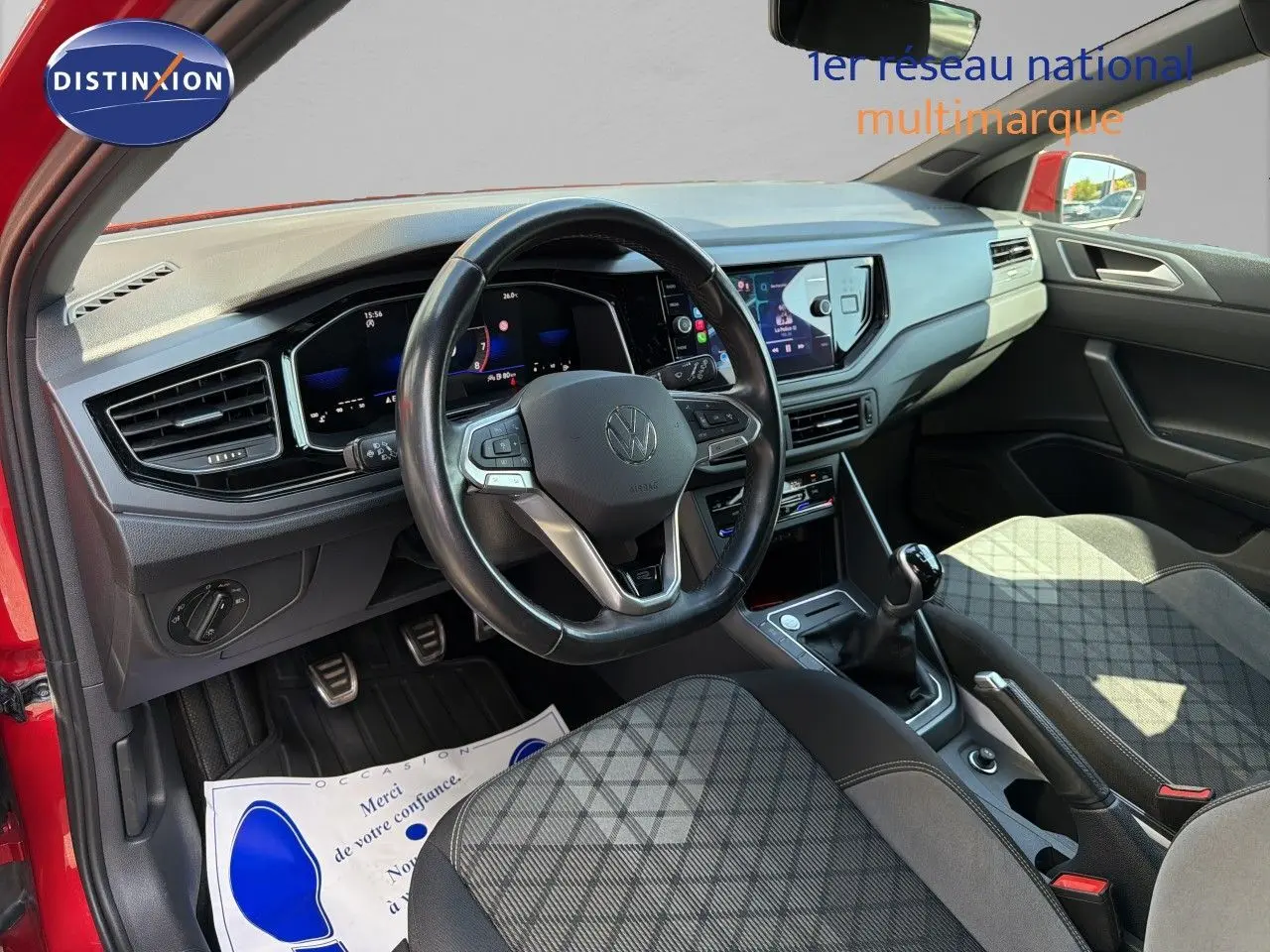 Vue intérieure côté conducteur d’une Volkswagen Polo rouge Roi 2023, volant multifonctions et tableau de bord digital visibles.