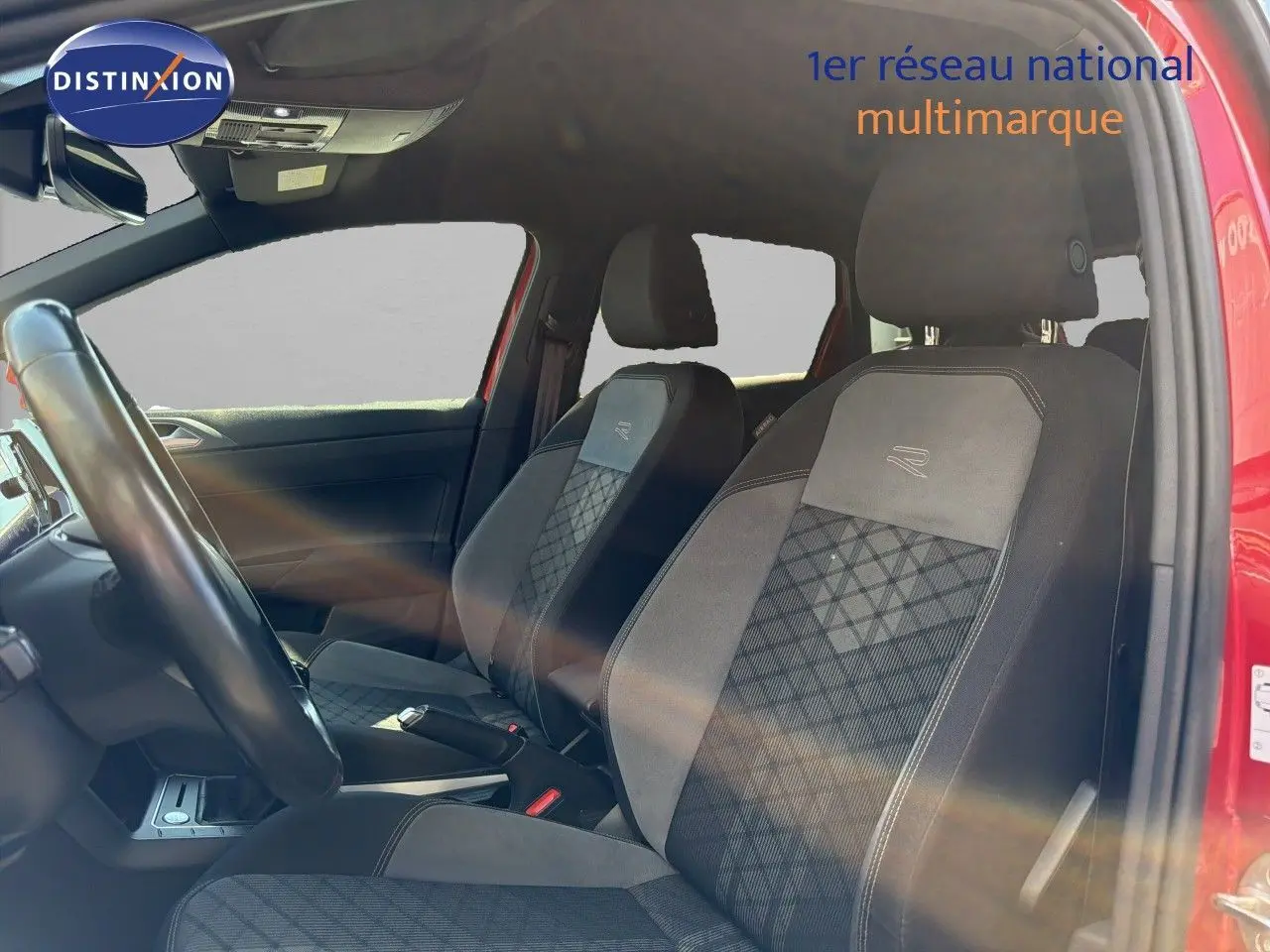 Vue intérieure côté conducteur de la Volkswagen Polo rouge Roi 2023, sièges R-Line avec surpiqûres et volant visible.