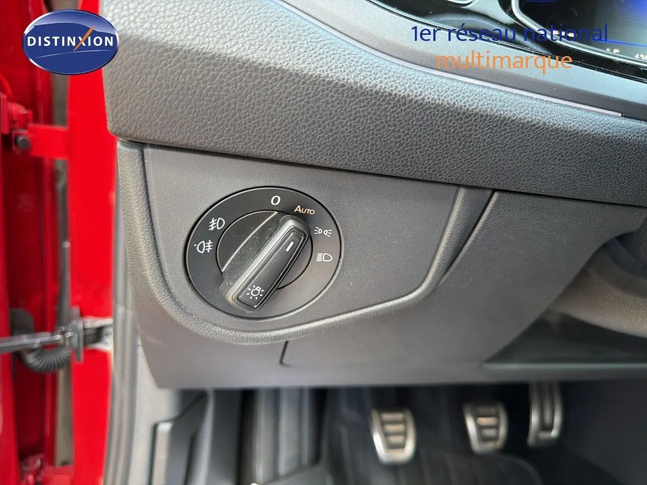 Gros plan sur le bouton de commande des phares dans l’habitacle d’une Volkswagen Polo rouge roi, côté conducteur.