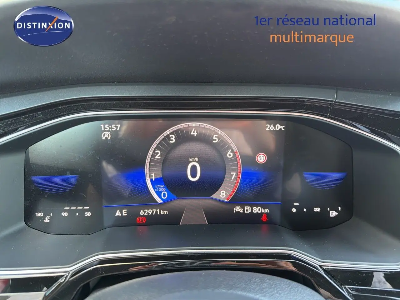 Vue rapprochée du tableau de bord numérique de la Volkswagen Polo rouge, affichant la vitesse à 0 km/h et 62 971 km au compteur.
