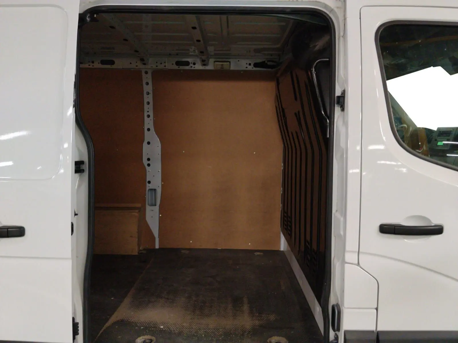 Vue intérieure de la zone de chargement du Renault Master blanc 2023, avec parois en bois et sol noir antidérapant.