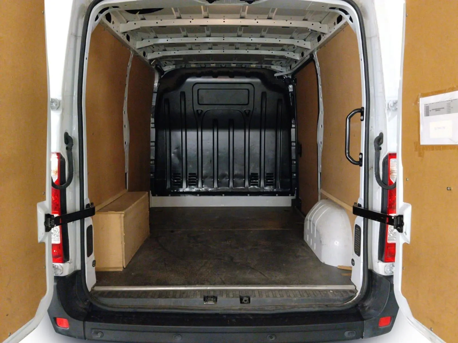 Vue arrière du Renault Master blanc L1H1 2023, montrant l’espace de chargement vide avec parois en bois et sol noir.