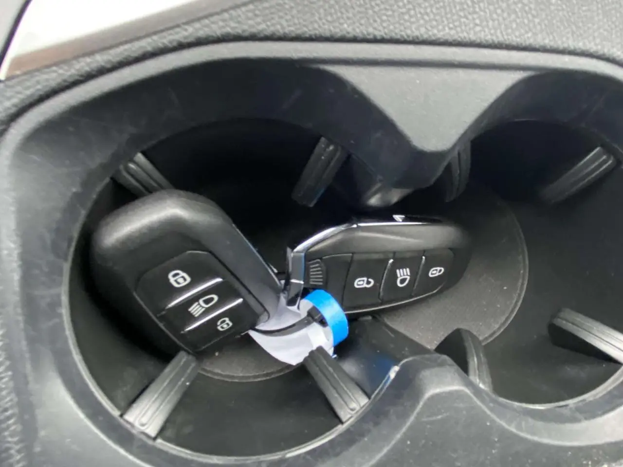 Gros plan sur deux clés de contact Peugeot 3008 posées dans les porte-gobelets noirs du véhicule.