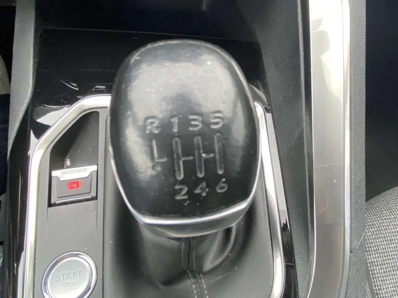 Le levier de vitesse manuel noir de la Peugeot 3008 blanc nacré, vu en gros plan depuis l'intérieur.