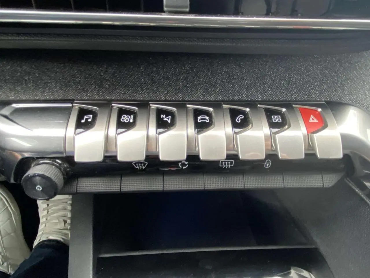 Gros plan sur la rangée de boutons argentés du tableau de bord du Peugeot 3008 blanc, avec commande de musique et alertes.