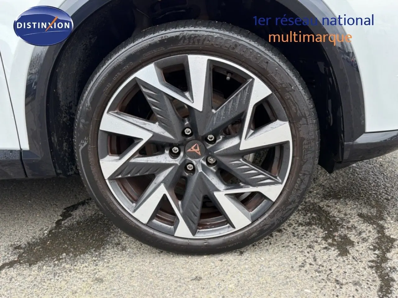 Gros plan sur la roue avant gauche de la CUPRA Formentor blanc neige métal avec jante alliage au design géométrique.